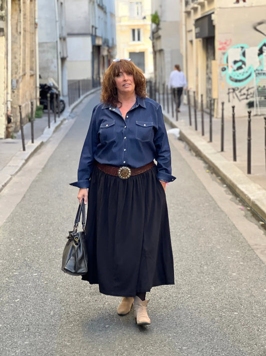 FEMME PLUS SIZE PORTANT UNE JUPE NOIRE AVEC UNE CHEMIISE EN JEAN ET UNE CEINTURE EN CUIR AVEC UNE BOUCLE EN RESINE MARRON