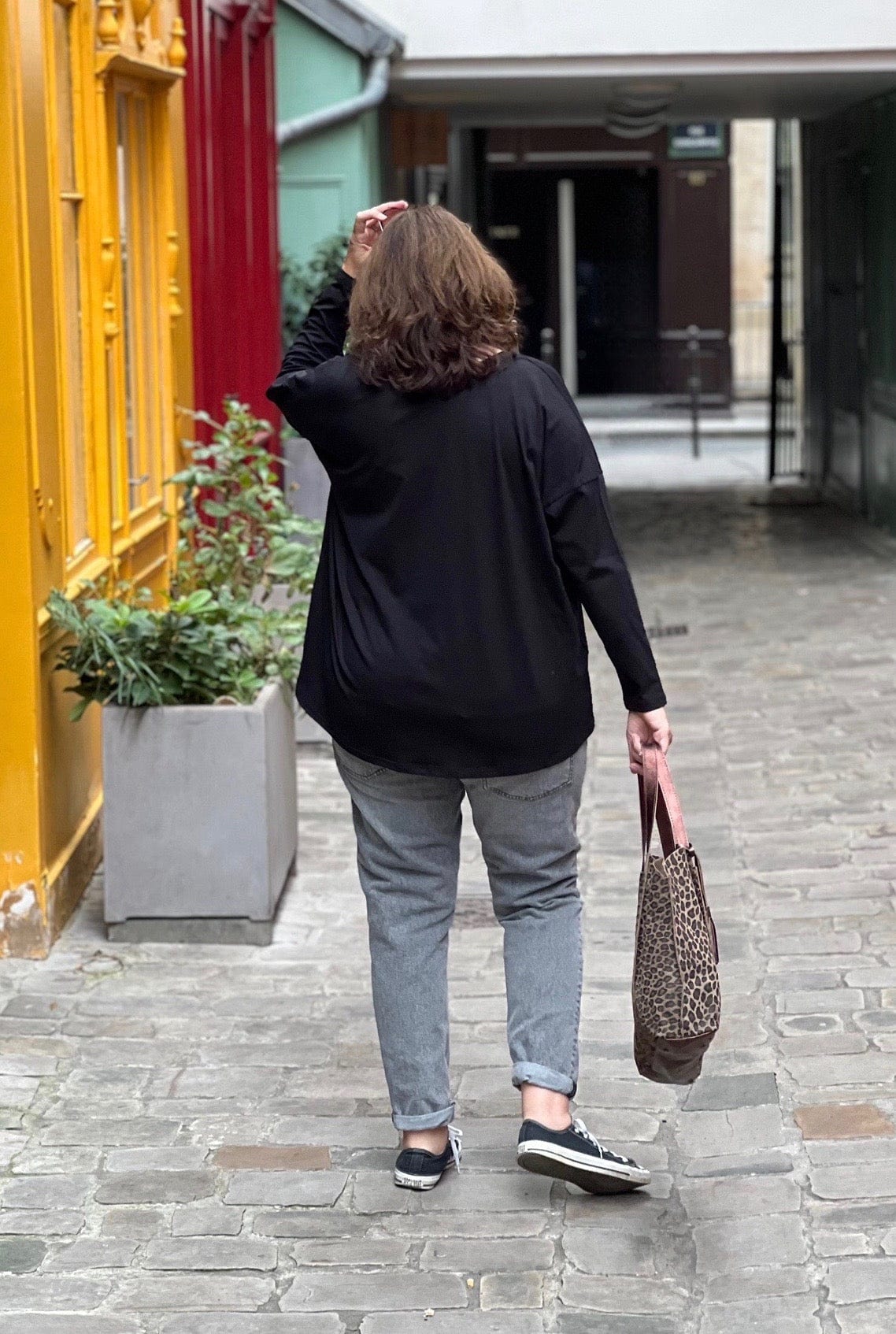 Tee shirt grande taille femme manches longues noir porté avec un jean gris. Vue de dos