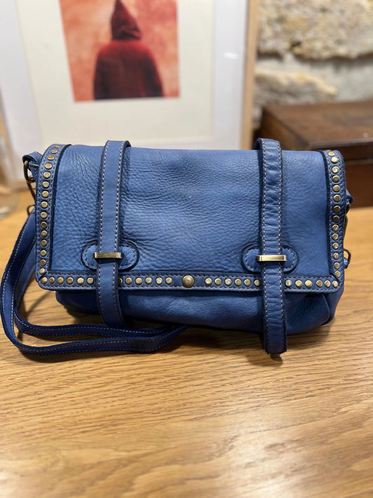 Sac bandoulière cuir bleu vintage posé sur une table